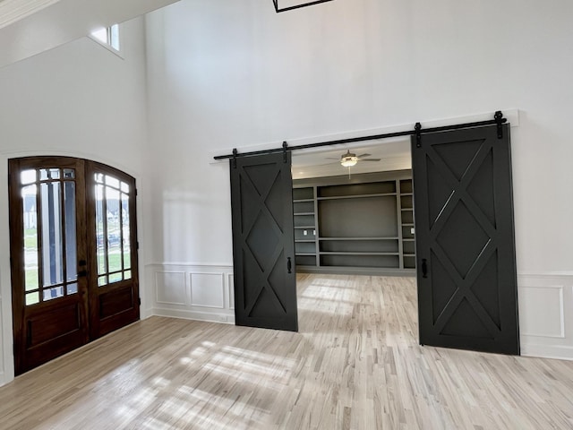 foyer entrance featuring light wood-type flooring, french doors, a wealth of natural light, and a barn door