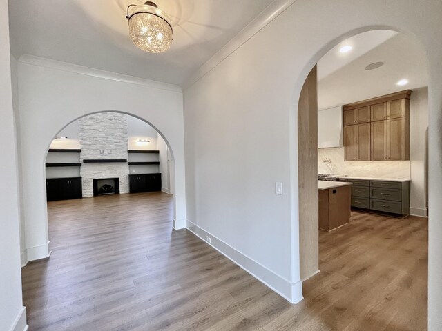 hallway featuring a notable chandelier, ornamental molding, and light hardwood / wood-style floors