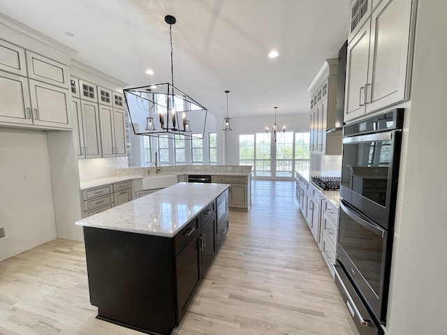 kitchen featuring pendant lighting, a center island, black double oven, tasteful backsplash, and a chandelier