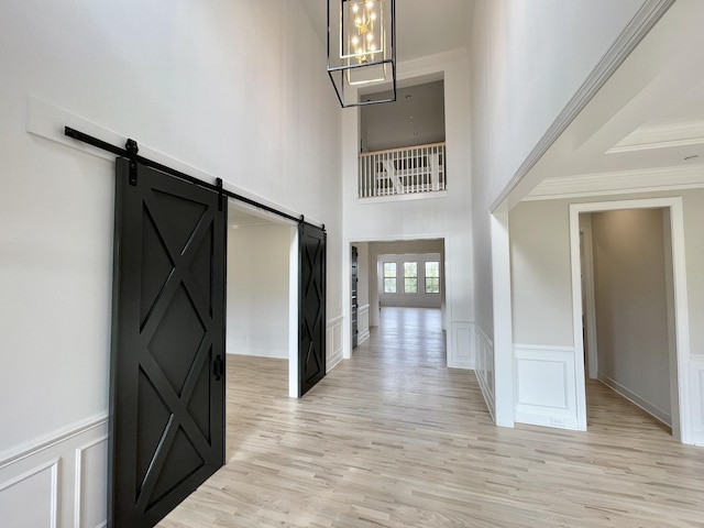 entrance foyer featuring light hardwood / wood-style flooring, ornamental molding, and a barn door