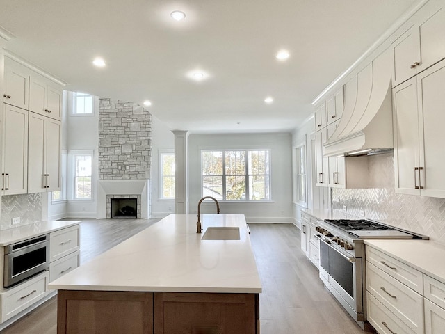 kitchen with sink, tasteful backsplash, a kitchen island with sink, and stainless steel appliances