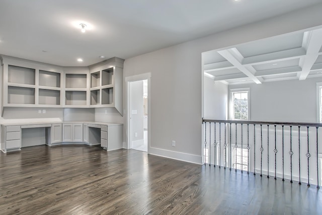 unfurnished office with coffered ceiling, dark hardwood / wood-style flooring, beamed ceiling, and built in desk