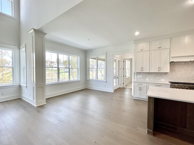 kitchen with plenty of natural light, white cabinetry, light hardwood / wood-style flooring, and tasteful backsplash