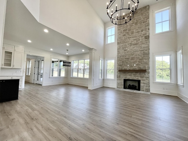 unfurnished living room featuring light hardwood / wood-style flooring, a towering ceiling, and a healthy amount of sunlight