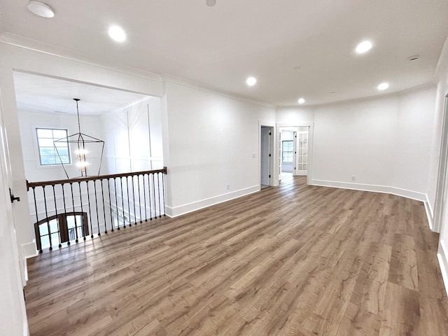 spare room with hardwood / wood-style flooring, crown molding, and a chandelier