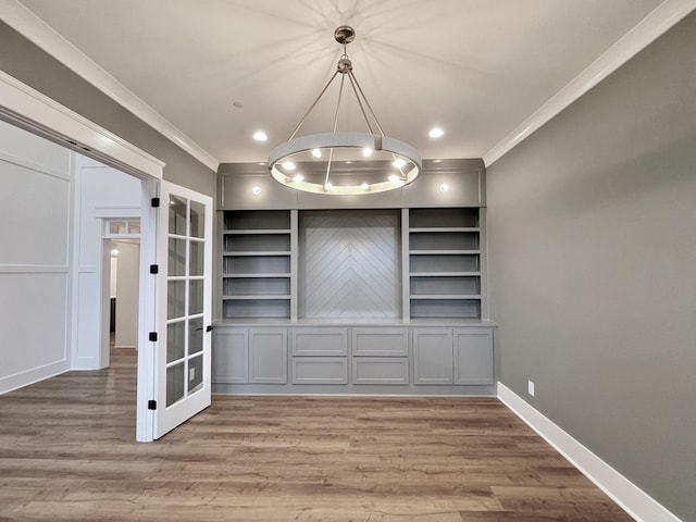 unfurnished dining area featuring hardwood / wood-style flooring, built in shelves, and crown molding