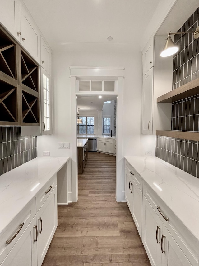 kitchen featuring backsplash, light wood-type flooring, white cabinets, and light stone countertops