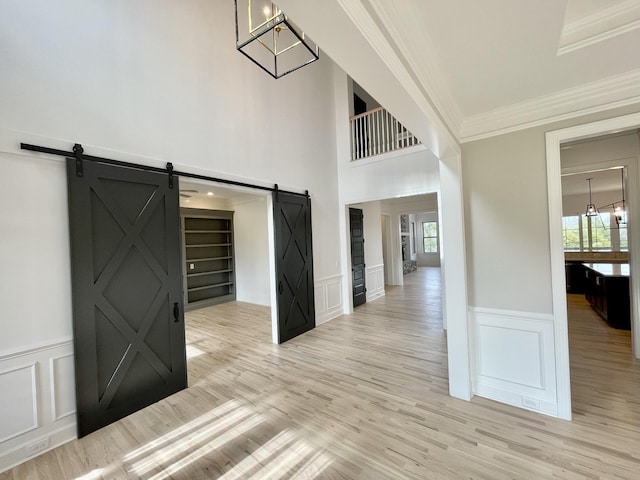 corridor featuring ornamental molding, light hardwood / wood-style flooring, and a barn door