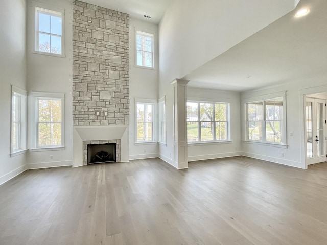 unfurnished living room featuring hardwood / wood-style flooring, plenty of natural light, and a stone fireplace