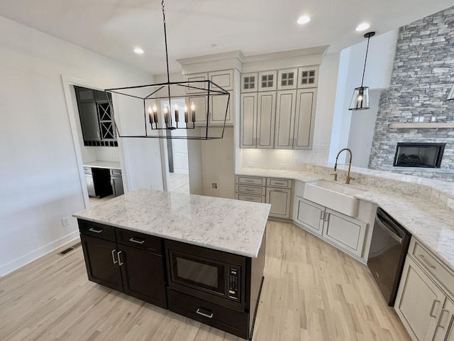 kitchen with sink, black appliances, decorative light fixtures, and light stone countertops