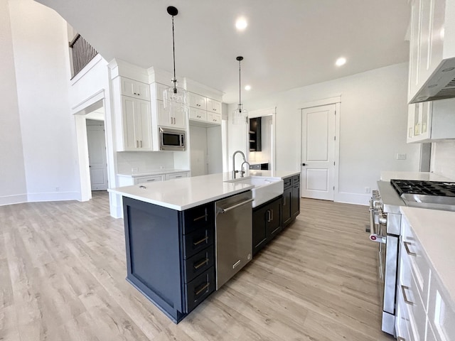 kitchen featuring pendant lighting, sink, white cabinetry, an island with sink, and stainless steel appliances