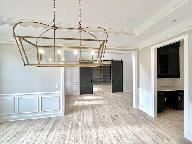 interior space featuring crown molding, a barn door, and light wood-type flooring