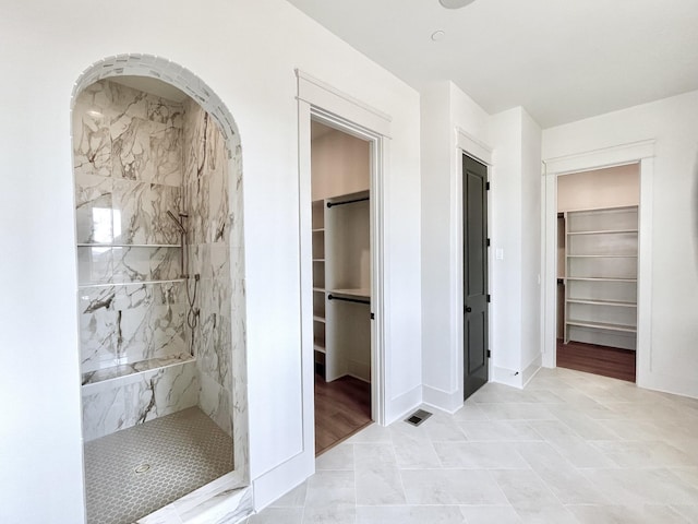 bathroom with a tile shower and tile patterned flooring