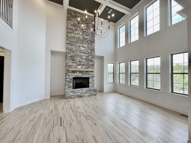 unfurnished living room featuring coffered ceiling, a high ceiling, a stone fireplace, and ornamental molding