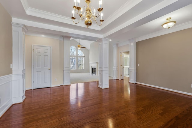 unfurnished living room featuring ornate columns, crown molding, a raised ceiling, dark hardwood / wood-style flooring, and ceiling fan