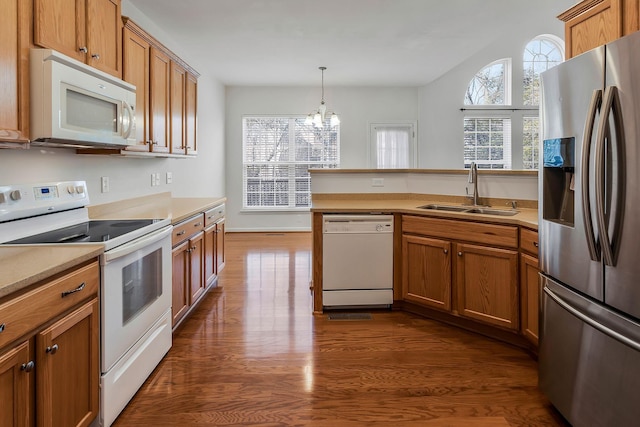 kitchen with white appliances, decorative light fixtures, sink, dark hardwood / wood-style floors, and a notable chandelier