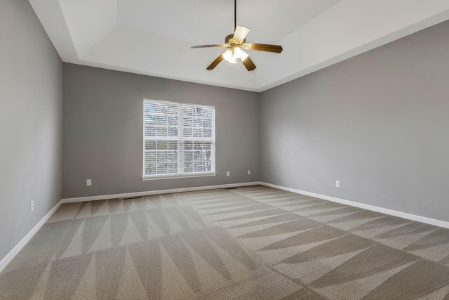 empty room featuring ceiling fan, light carpet, and a tray ceiling