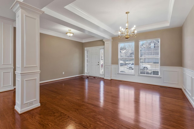 foyer with crown molding, a raised ceiling, ornate columns, dark hardwood / wood-style floors, and a notable chandelier