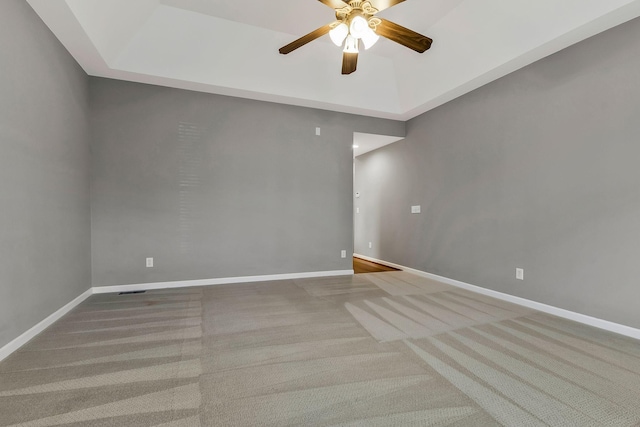 unfurnished room featuring light carpet, a high ceiling, ceiling fan, and a raised ceiling