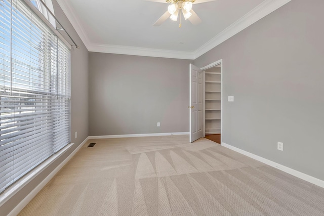 carpeted empty room with ceiling fan and crown molding