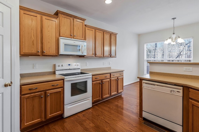 kitchen with white appliances, dark hardwood / wood-style floors, a notable chandelier, and hanging light fixtures