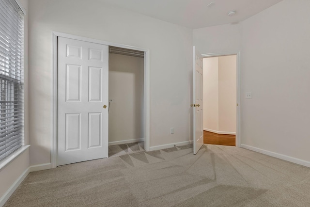 unfurnished bedroom with a closet and light carpet