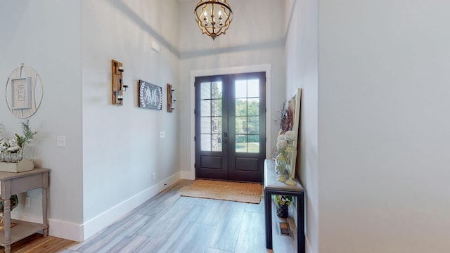 entryway featuring french doors, a chandelier, and light wood-type flooring