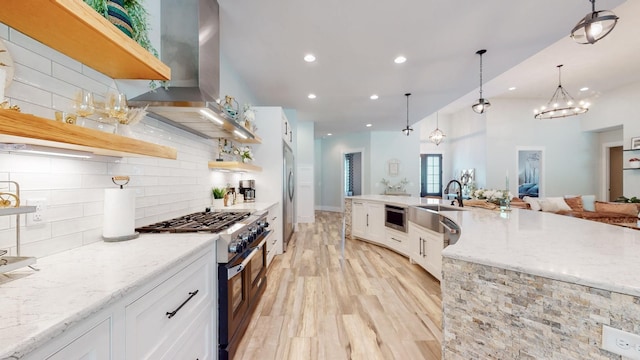 kitchen with decorative light fixtures, white cabinetry, light stone countertops, exhaust hood, and stainless steel appliances