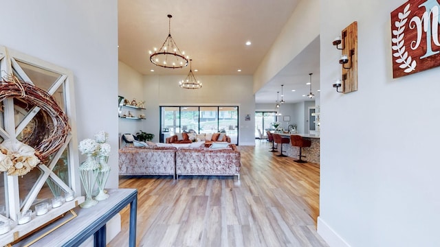 living room featuring an inviting chandelier, light hardwood / wood-style flooring, and a high ceiling