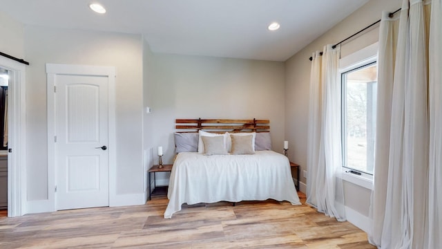 bedroom with light wood-type flooring and a barn door