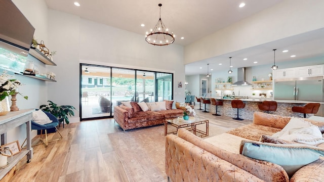 living room featuring a towering ceiling, a notable chandelier, and light wood-type flooring