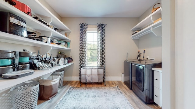 laundry area featuring washing machine and clothes dryer and light hardwood / wood-style flooring