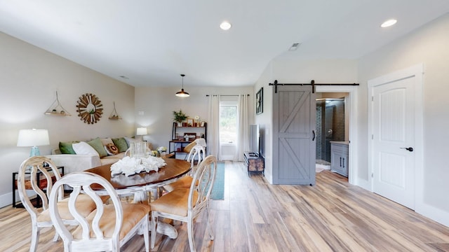 dining room featuring a barn door and light hardwood / wood-style flooring