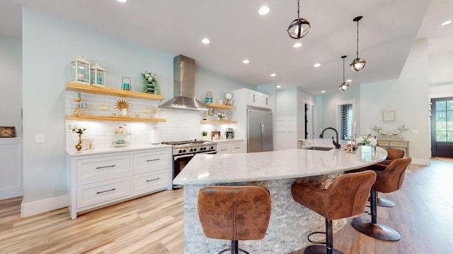 kitchen with pendant lighting, white cabinetry, wall chimney range hood, stainless steel appliances, and decorative backsplash