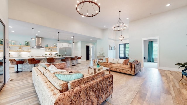 living room featuring light wood-type flooring, a chandelier, and a high ceiling