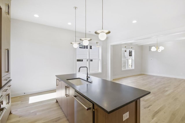 kitchen featuring sink, light hardwood / wood-style flooring, an island with sink, decorative light fixtures, and stainless steel dishwasher