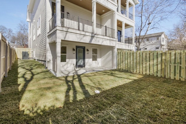 back of property featuring a balcony, a yard, and central AC unit