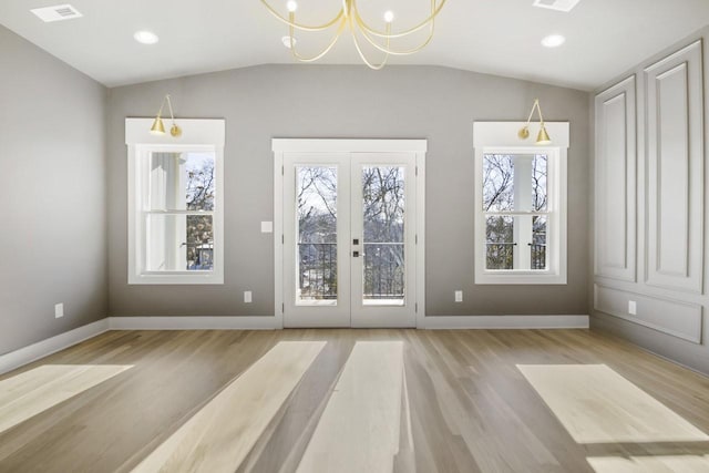 entryway with french doors, a notable chandelier, lofted ceiling, and light wood-type flooring