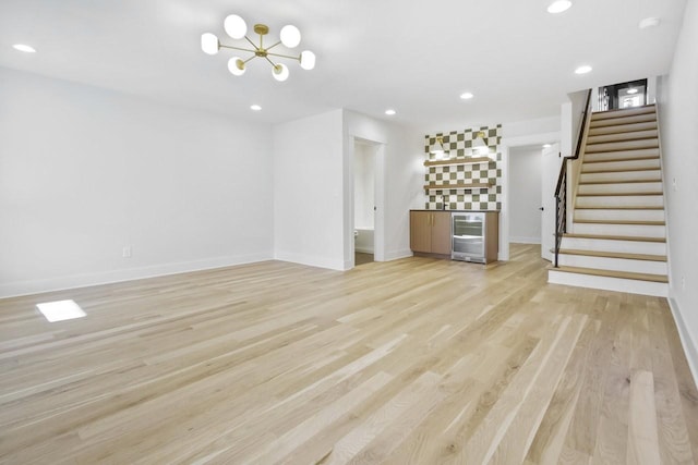 unfurnished living room featuring bar area, beverage cooler, and light wood-type flooring