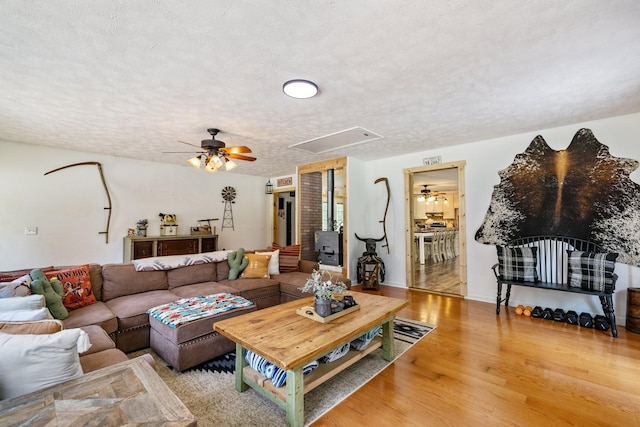 living room featuring ceiling fan, light hardwood / wood-style flooring, and a textured ceiling