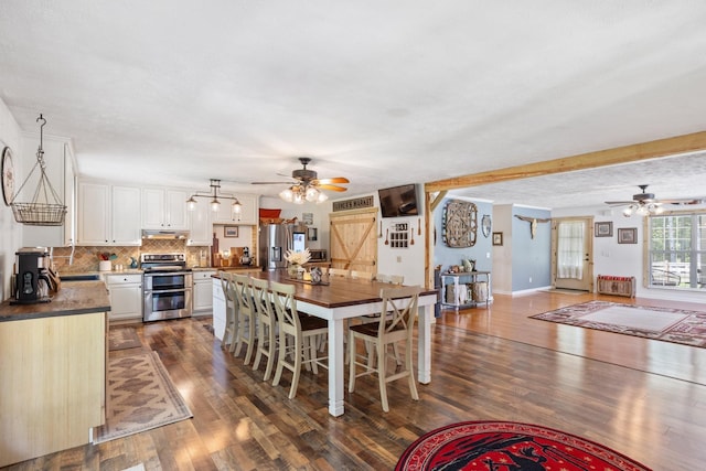 dining area with ceiling fan, dark wood-type flooring, and a textured ceiling