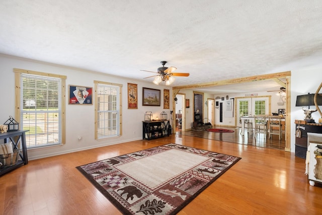 living room with hardwood / wood-style flooring, a textured ceiling, and ceiling fan