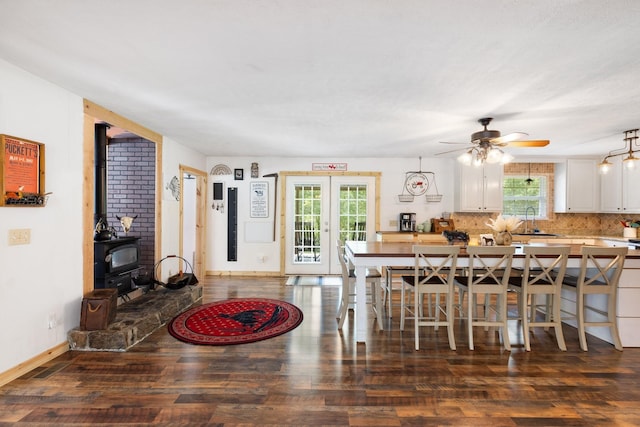 dining space featuring dark wood-type flooring, a wood stove, a wealth of natural light, and sink