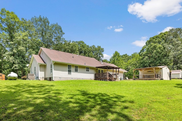 rear view of house featuring an outdoor structure, a lawn, and a wooden deck