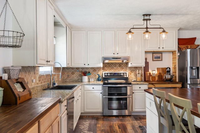 kitchen featuring hanging light fixtures, sink, white cabinets, wood counters, and stainless steel appliances