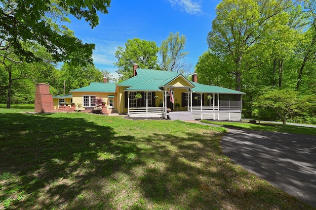 view of front of property featuring a porch, a sunroom, and a front lawn