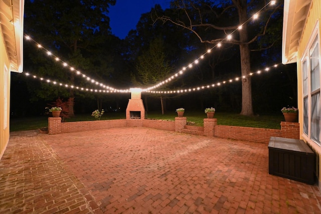 yard at night with a patio and exterior fireplace