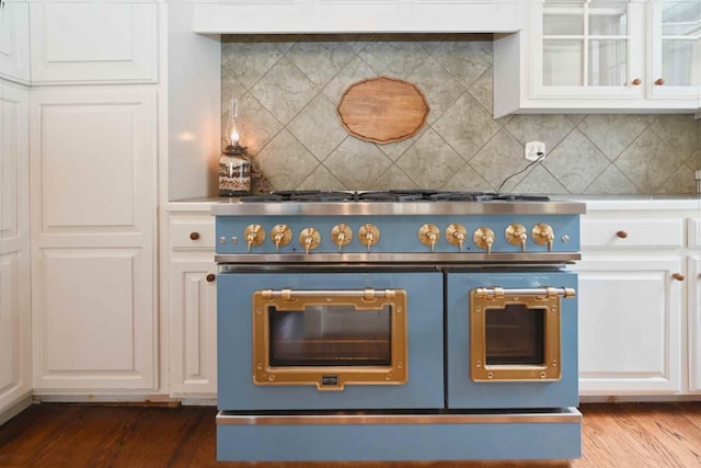 kitchen featuring wood-type flooring, backsplash, range with two ovens, and white cabinets