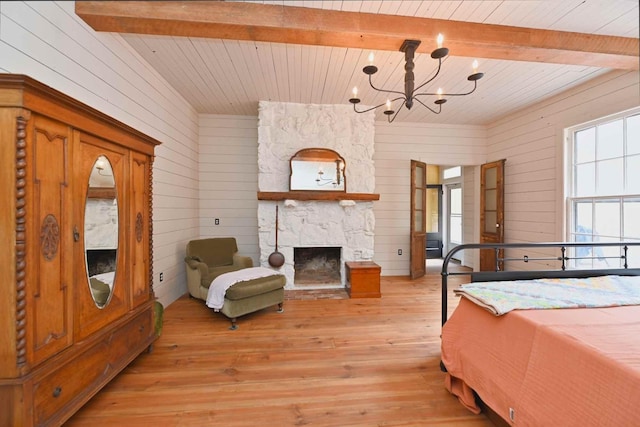 bedroom featuring wooden walls, beamed ceiling, and a stone fireplace