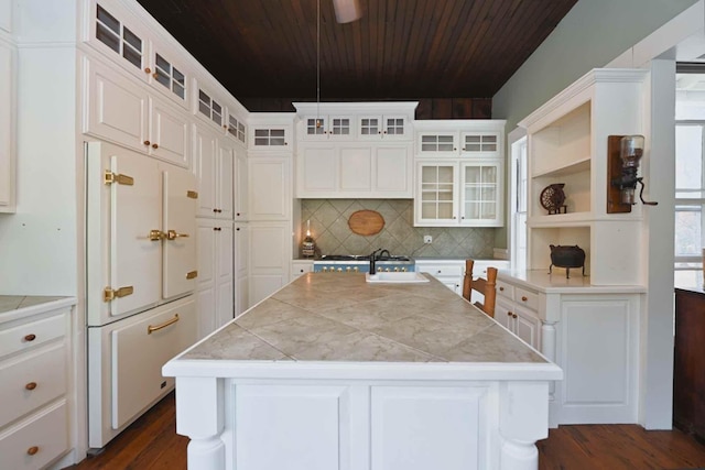 kitchen with fridge, white cabinetry, decorative backsplash, sink, and a center island with sink